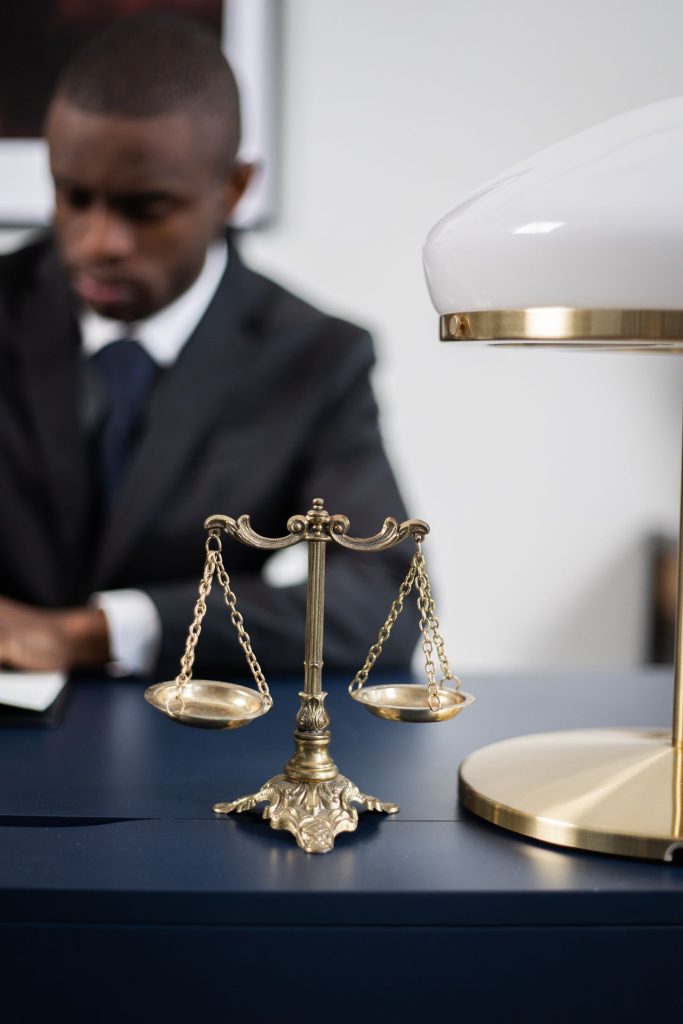 Prendre rendez-vous avec un avocat en ligne : avocat travaillant à son bureau près d'une balance de la justice